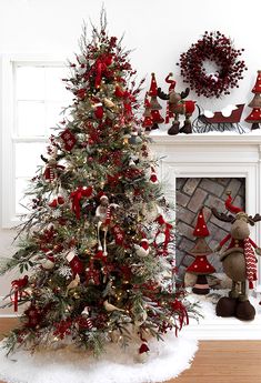 a decorated christmas tree in front of a fireplace with red and white decorations on it