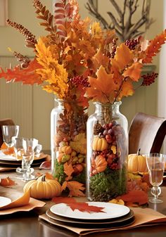 the table is set for thanksgiving dinner with fall leaves and gourds in glass jars