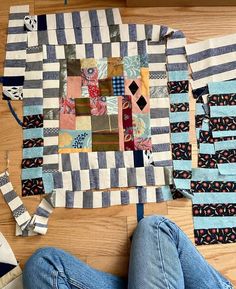 someone is laying on the floor next to some pieces of fabric that have been cut into squares