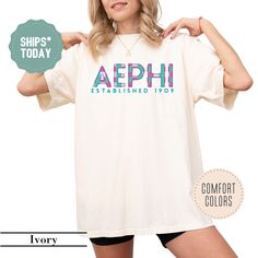 a woman wearing a white shirt with the words aephi established in blue and pink