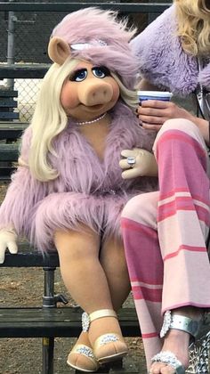 a woman sitting on top of a bench next to a large stuffed animal in a pink outfit