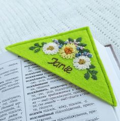 a bookmark with flowers on it sitting next to an open book