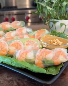 shrimp spring rolls with dipping sauce on a tray in front of a potted plant