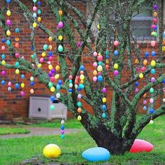 an easter tree decorated with colorful eggs in front of a brick building