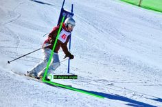 a man riding skis down the side of a snow covered slope next to a flag