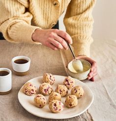 a woman is spooning something out of a bowl on a plate next to some cookies