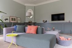 a living room filled with furniture and a flat screen tv mounted on the wall above it