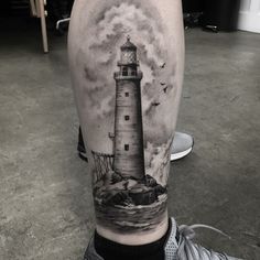 a man's leg with a lighthouse tattoo on it