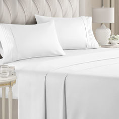 a bed with white sheets and pillows on it