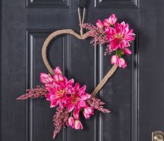 a heart shaped wreath with pink flowers hanging on a door