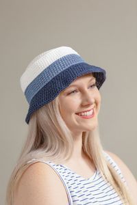 a woman with blonde hair wearing a blue and white crochet beanie hat