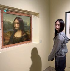 a woman standing in front of two paintings