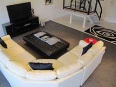 a living room with white couches and a black coffee table in front of a flat screen tv