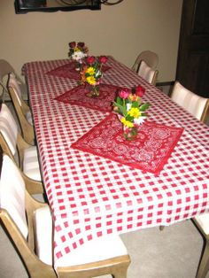 the table is set with red and white checkered cloths, flowers in vases