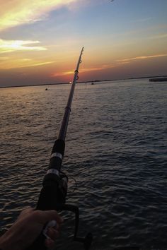 someone is fishing on the water at sunset or dawn with their rod and reel in hand