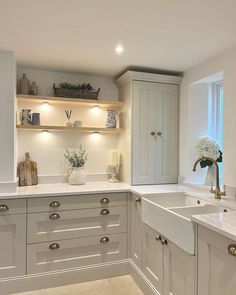 a white kitchen with lots of counter space and open shelving above the sink area