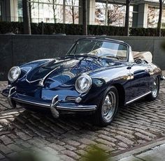 a blue sports car parked in front of a tall building on a cobblestone street