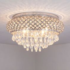 a crystal chandelier hanging from the ceiling in a room with white walls and flooring