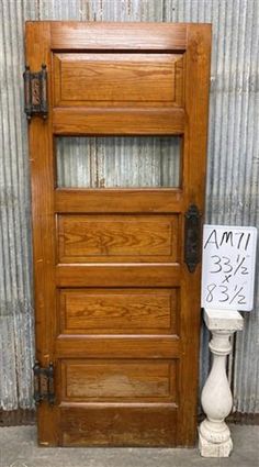 a wooden door sitting next to a white pedestal