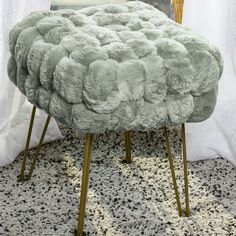 a foot stool made out of sheepskin with gold legs