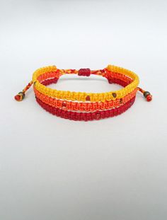 two orange and yellow bracelets with beads on white background, side by side in front of each other