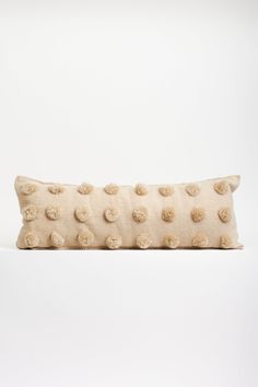 a white pillow with pom - poms sitting on top of it's side