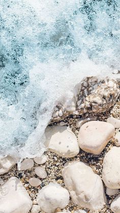 rocks and pebbles on the beach with waves crashing in to shore, closeup view