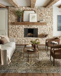 a living room filled with furniture and a fire place in front of a stone wall