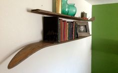 a shelf with books and vases on top of it in a corner next to a green wall