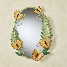 a mirror with some butterflies on it and green leaves around the edges that are painted yellow