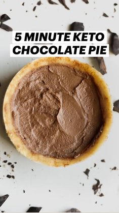 a cookie with chocolate frosting sitting on top of a white table covered in black pieces