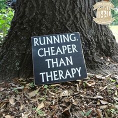 a running cheaper than therapy sign in front of a tree with leaves on the ground