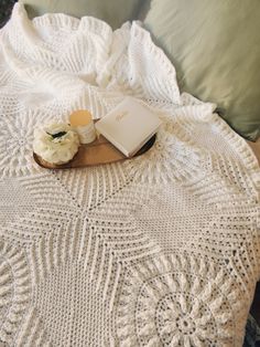 a white crocheted blanket sitting on top of a bed next to a pillow