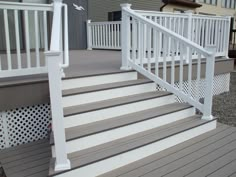 a white railing on the side of a gray and white porch with steps leading up to it