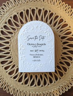 save the date coaster on a woven place mat with an ornate design and white lettering