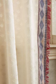 a curtain with fringes hanging from it's side next to a window sill