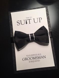 a black bow tie on top of a card with the words suit up in white lettering