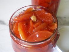 a jar filled with sliced up oranges on top of a white counter next to another jar