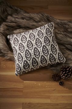 a black and white pillow sitting on top of a wooden floor next to a pine cone