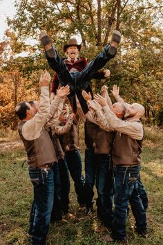 a group of men standing around each other in the middle of a field with their hands up