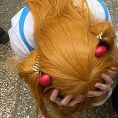 a woman with long red hair has her hands on her head and is looking down at the floor