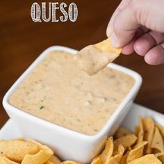 a hand dipping a tortilla chip into a bowl of quesadilla