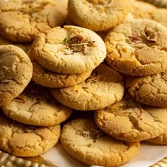 a pile of cookies sitting on top of a white and gold plate next to each other