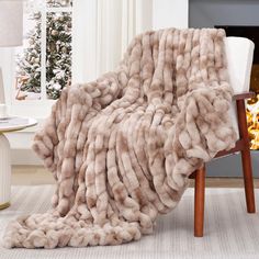 a blanket that is on top of a chair in front of a fire place and christmas tree