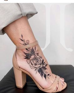 a woman's foot with a rose tattoo on the side of her leg and ankle