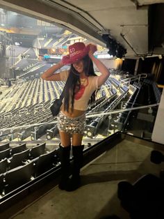 a woman in short shorts and boots stands on the bleachers at a stadium