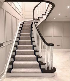 a white staircase with black handrails and grey carpet