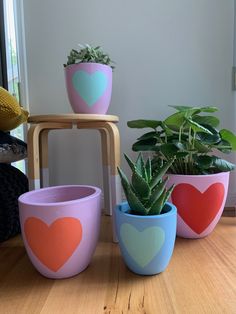 three potted plants with hearts painted on them sitting on a table next to a window