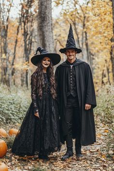 two people dressed up in witches costumes standing next to each other with pumpkins on the ground