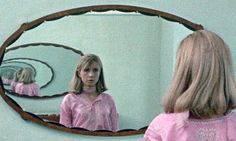 a woman standing in front of a mirror looking at herself in the mirror with her reflection